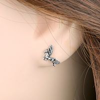Closeup of a Silver Pegasus Post Earrings in a model's ear, showing the lifelike sculpting of the horse's body.