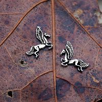 Closeup of a pair of Silver Pegasus Post Earrings on a brown leaf, showcasing their feathered wings and flowing tails.