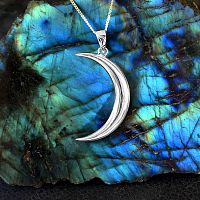Sterling Silver Lunar Magic Pendant showcased against a backdrop of a labradorite gemstone slab in vibrant blues and greens.