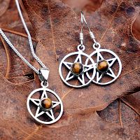 Silver Pentacle Earrings with Tiger Eye, resting on a leaf, alongside a pendant with the same design.