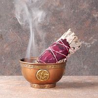 Smoldering Sage and Rose Bundle with a trickle of smoke, propped in a small copper bowl that sits on fireproof tile surface