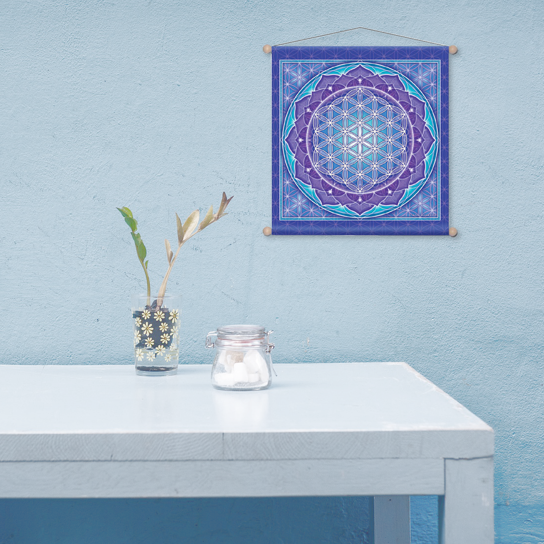 Minimalist scene evoking tranquility, an almost bare tabletop, and the Flower of Life banner hanging on a pale blue wall.