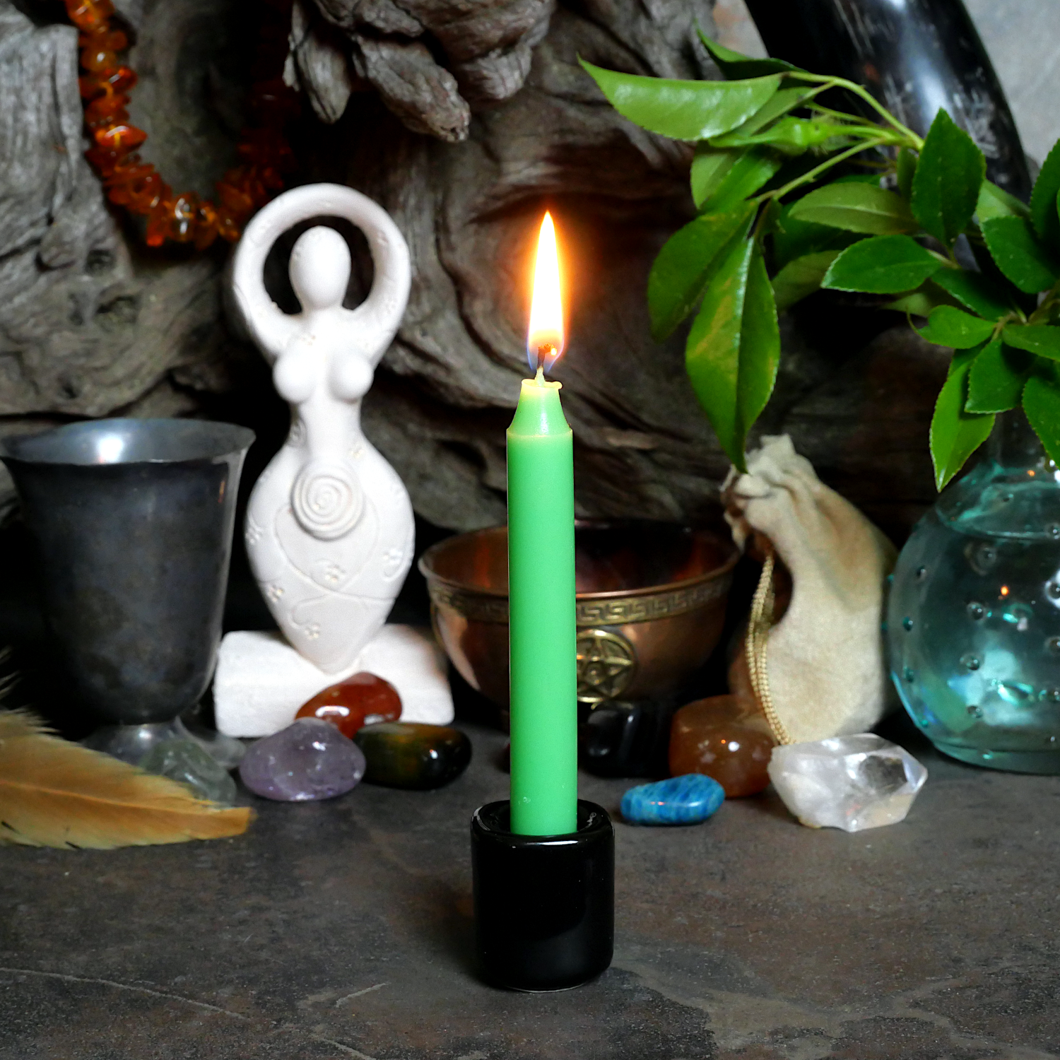 A lit Apple Green Chime Candle, in a personal altar display, showing how it might be used in a ritual or ceremonial setting.