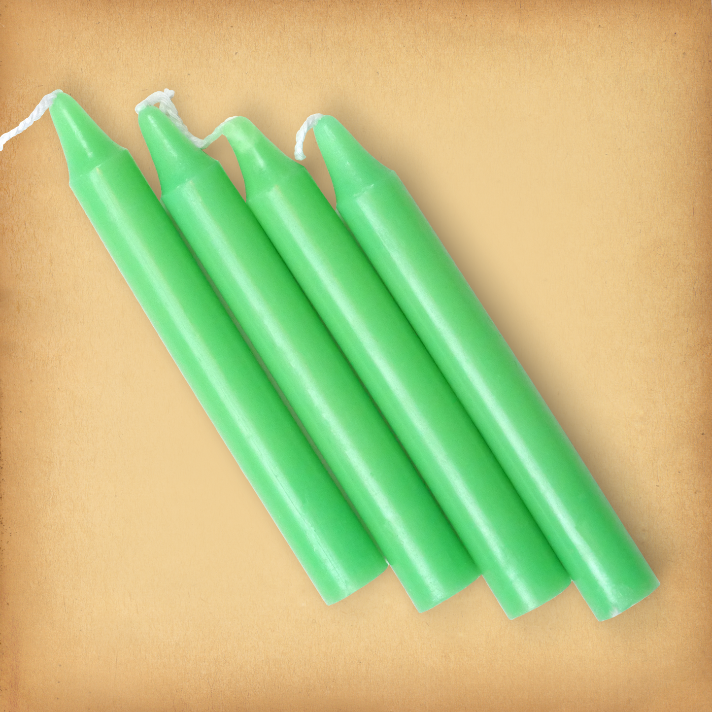 An overhead view of four Apple Green Chime Candles, diagonally placed on a plain surface, showing the candles' proportions.