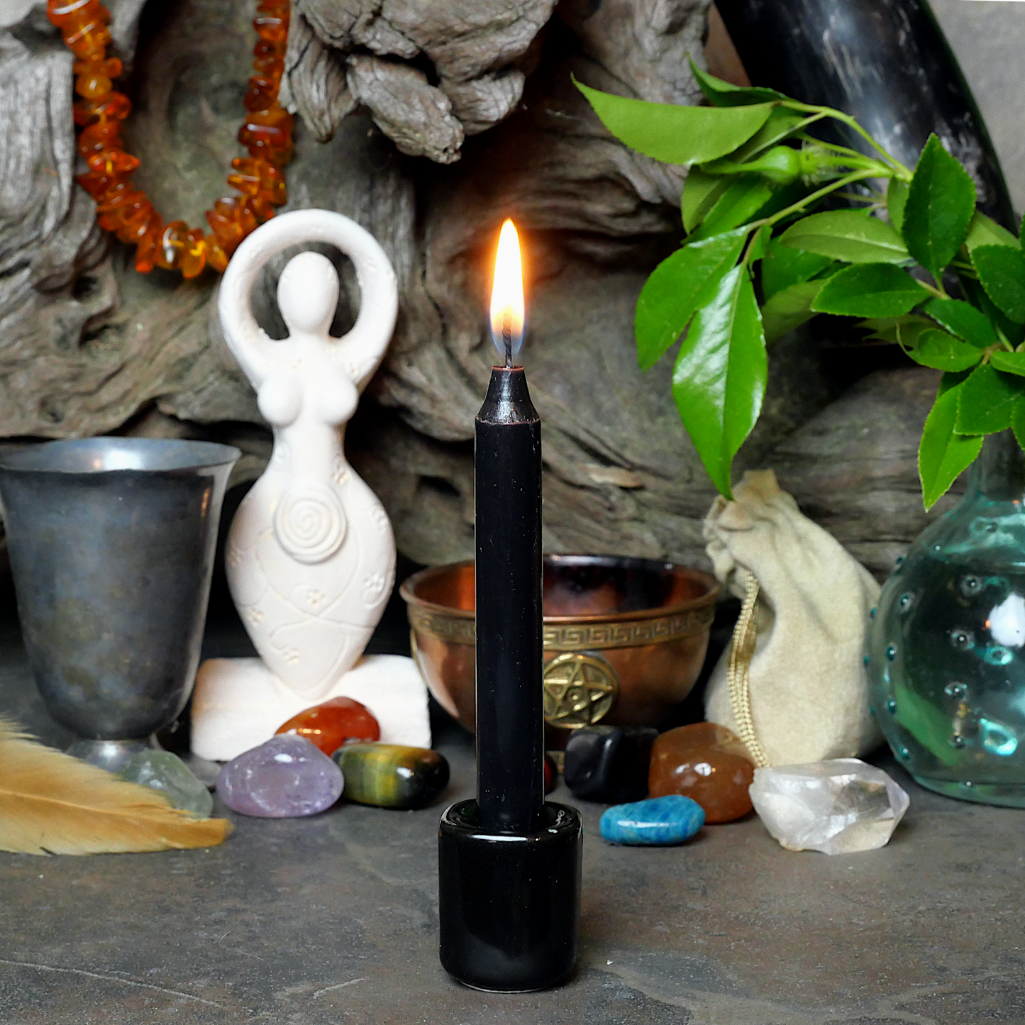 A lit Black Chime Candle, in a personal altar display, showing how it might be used in a ritual or ceremonial setting.
