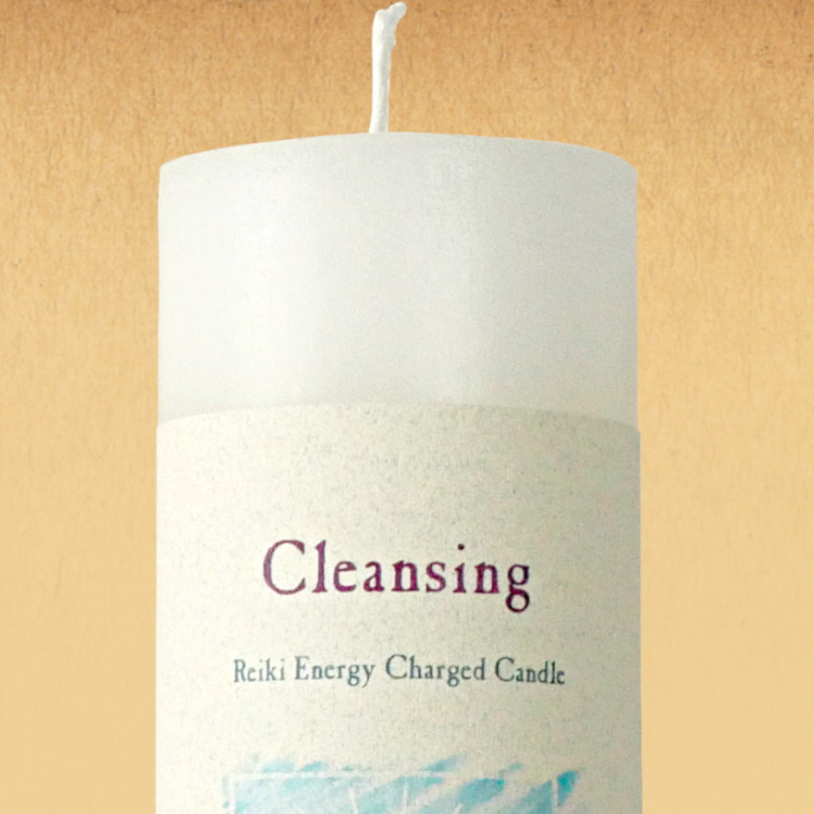 White pillar candle labeled “Cleansing” with “Reiki Energy Charged Candle”. Slim pillar candle with a single wick.