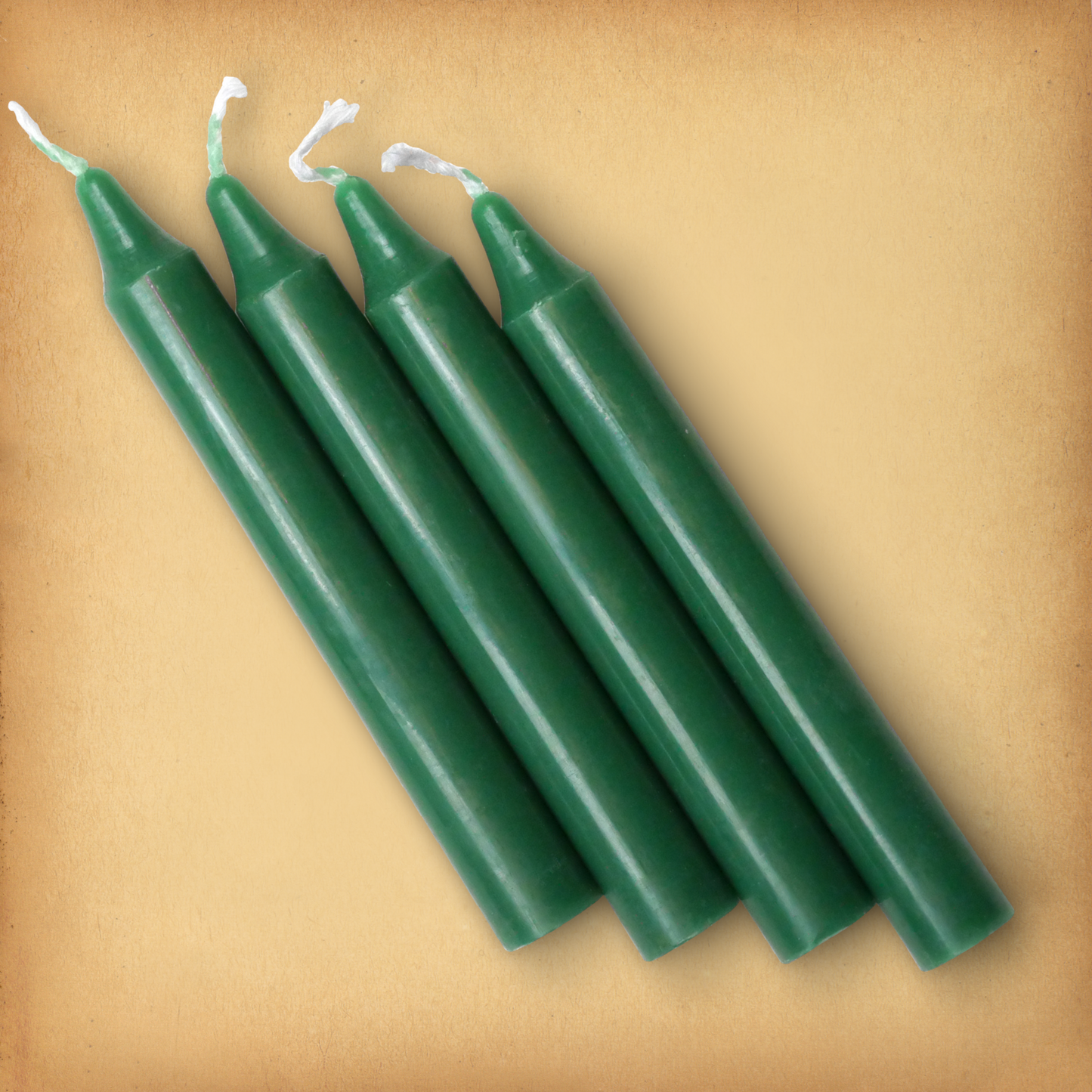 An overhead view of four forest Green Chime Candles, diagonally placed on a plain surface, showing the candles' proportions.