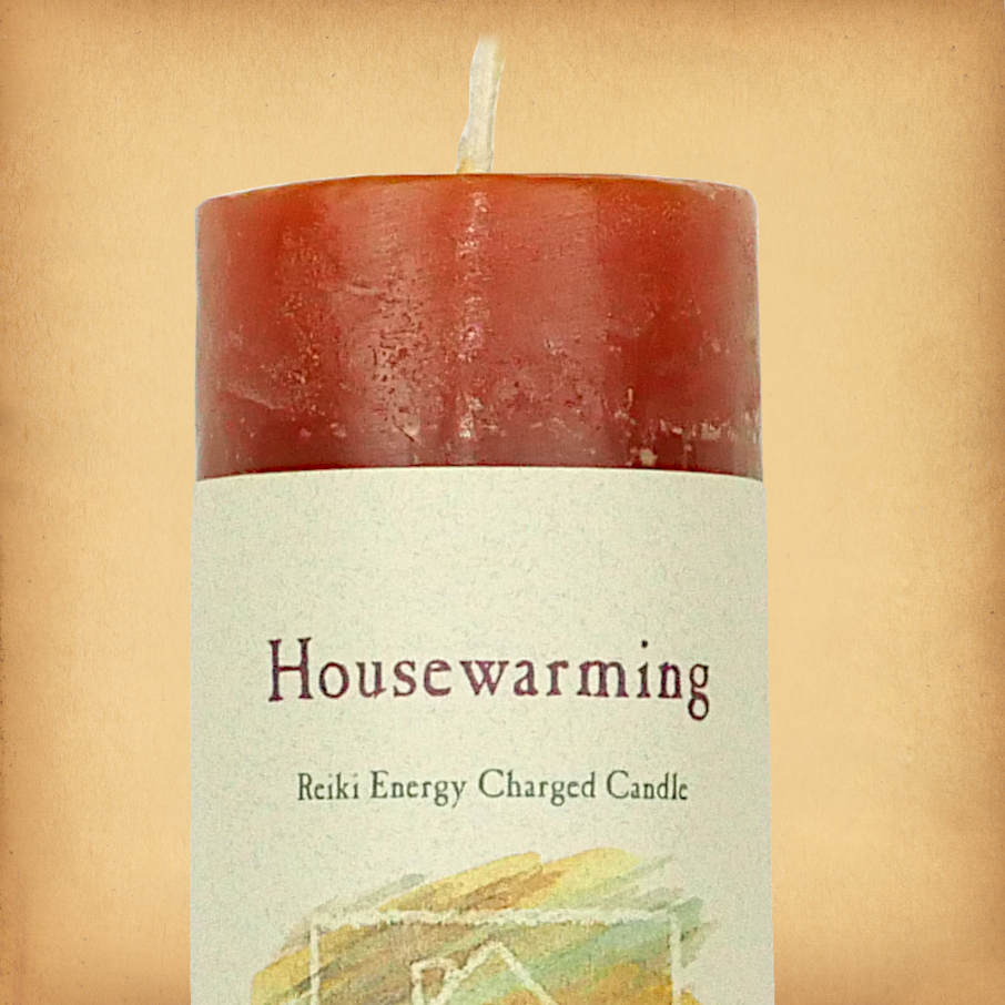 Orange pillar candle labeled “Housewarming” with “Reiki Energy Charged Candle” beneath. Slim pillar candle with a single wick