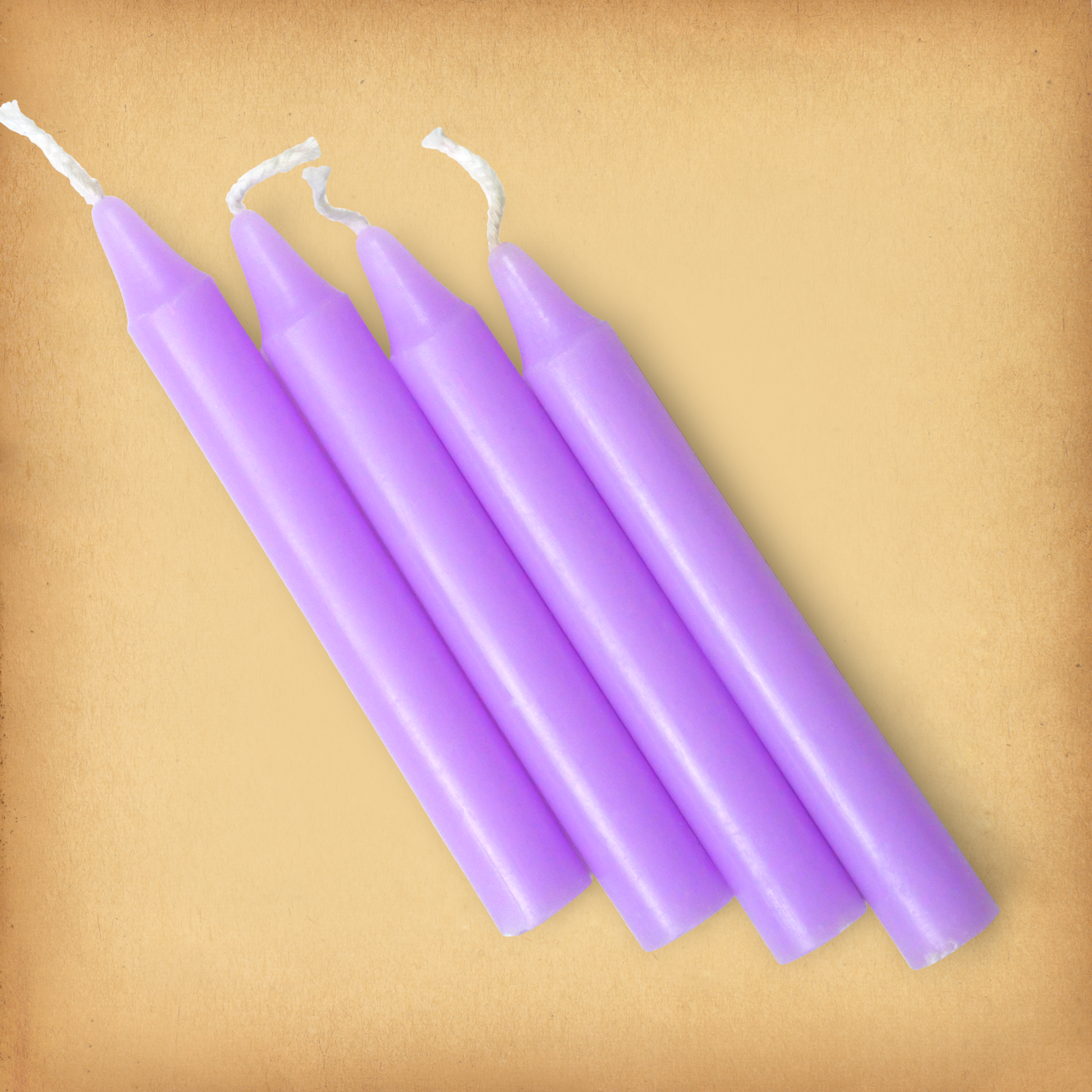 An overhead view of four Lavender Chime Candles, diagonally placed on a plain surface, showing the candles' proportions.