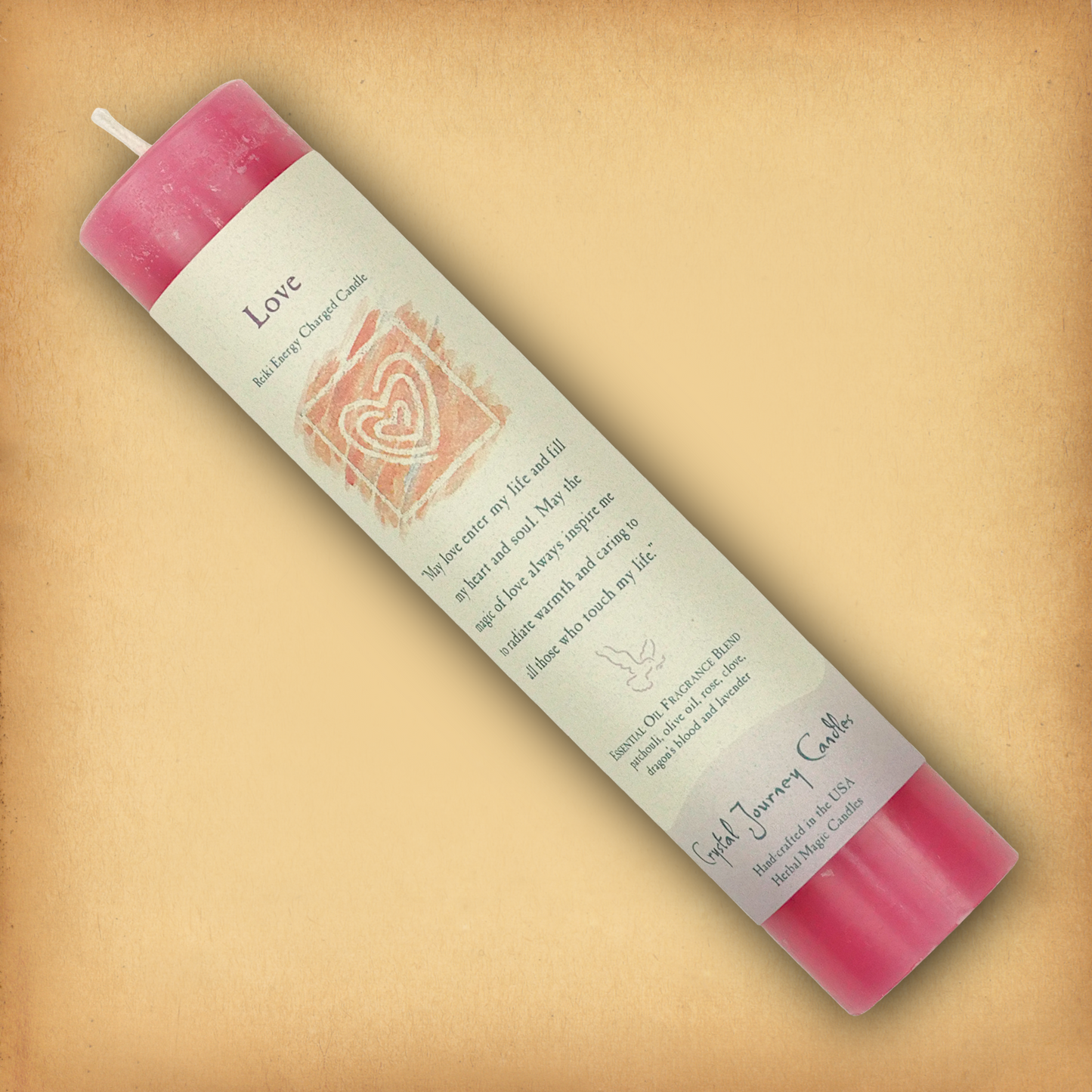 Pink Reiki-charged Love Pillar Candle, displayed diagonally to show its label with affirmation and essential oil blend.