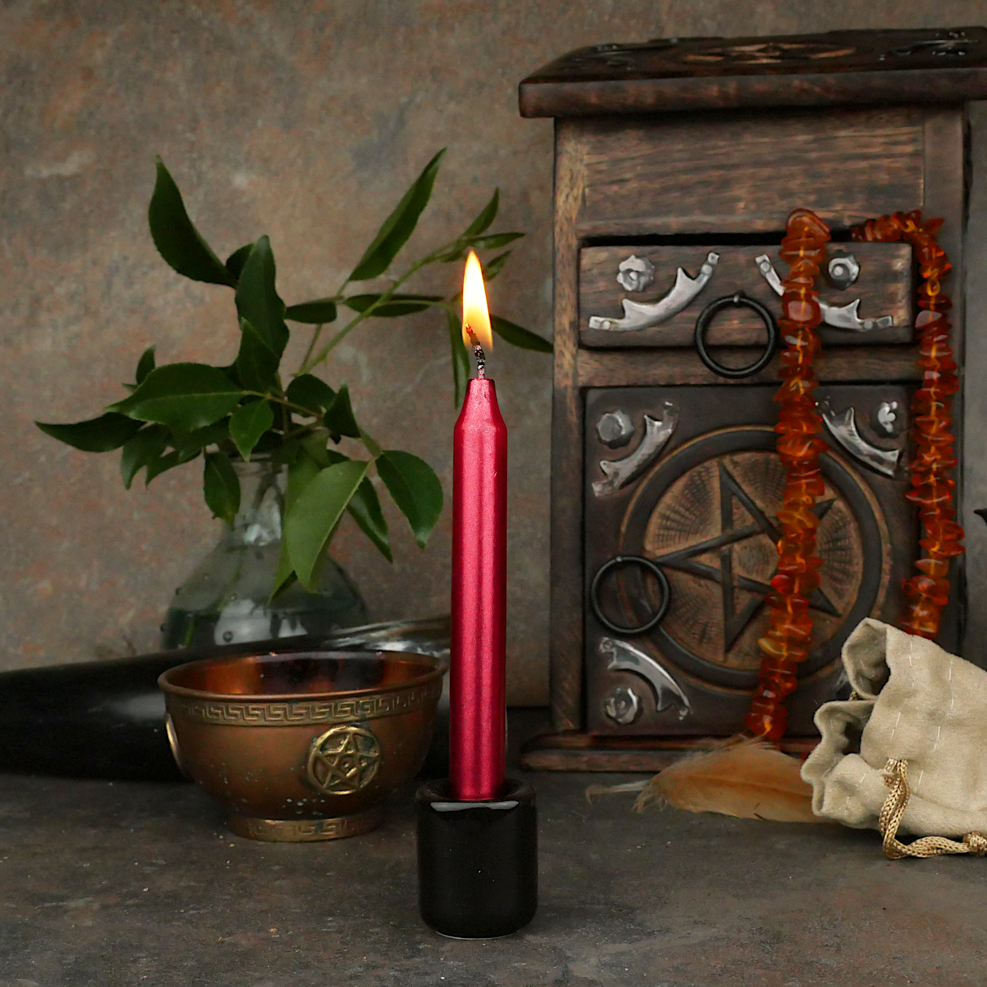 A lit Metallic Red Chime Candle, in a personal altar display, showing how it might be used in a ritual or ceremonial setting.
