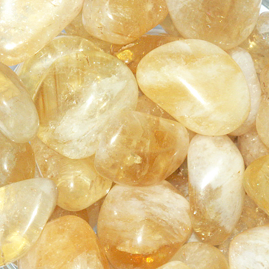Tumbled Citrine gemstones in sunny shades of yellow, gold, and white, with a mix of translucent and opaque areas.