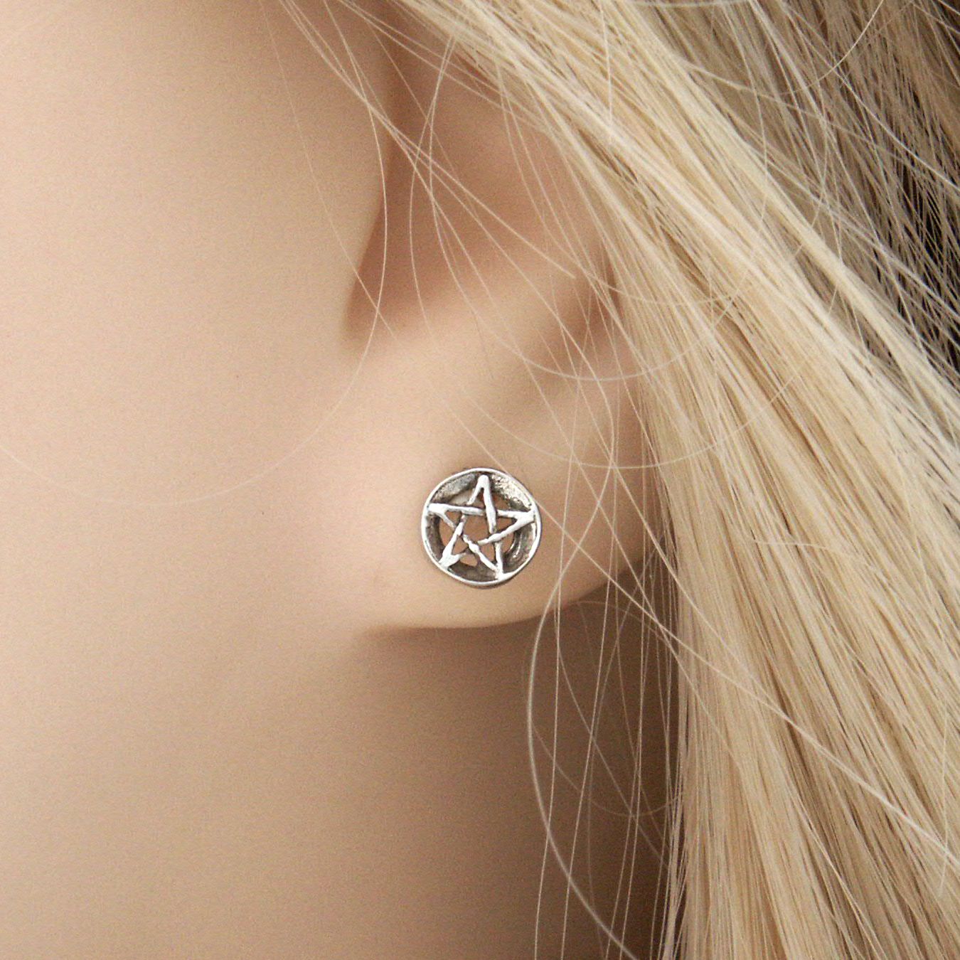 Closeup of a Silver Pentacle Post Earring in a model's ear, showing that it is designed for comfort and subtle style.