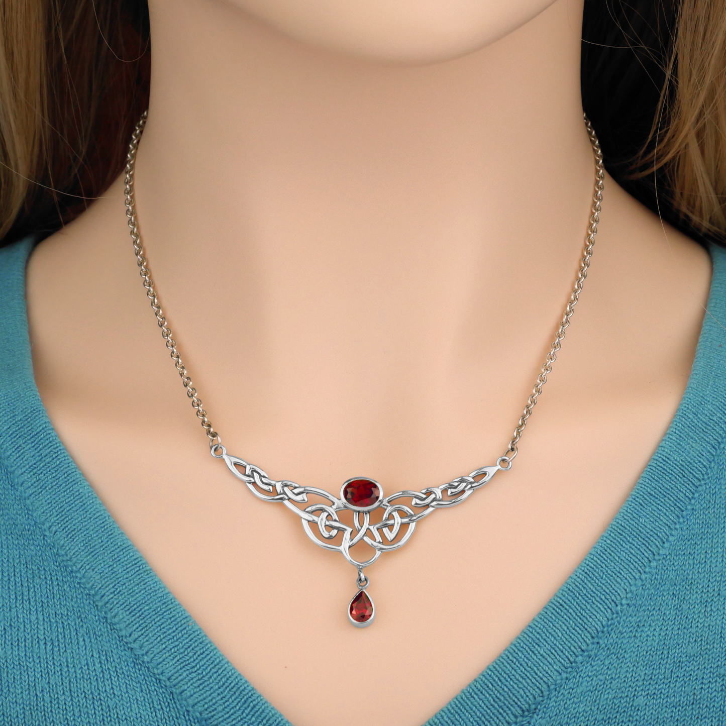 Elegant Sterling Silver Celtic Passion Necklace, worn by a model to display its graceful knotwork and vibrant garnet accents.