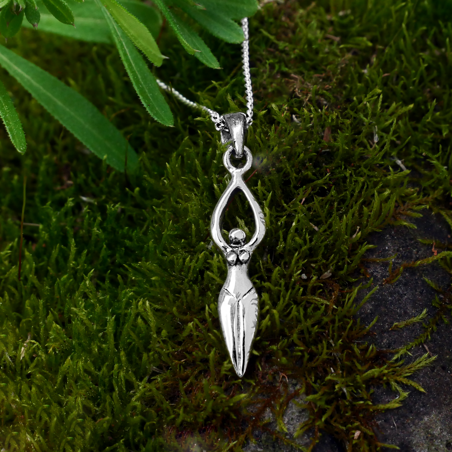 Sterling Silver Goddess Pendant shown on a background of soft green moss, reflecting a connection to Nature and the Divine.