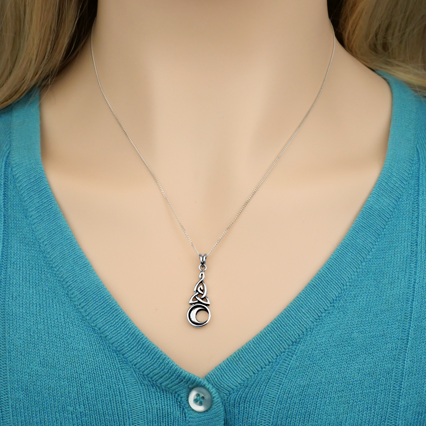 Sterling Silver Celtic Moon Pendant worn by a model, with the 18” chain holding the pendant just above her sweater’s neckline