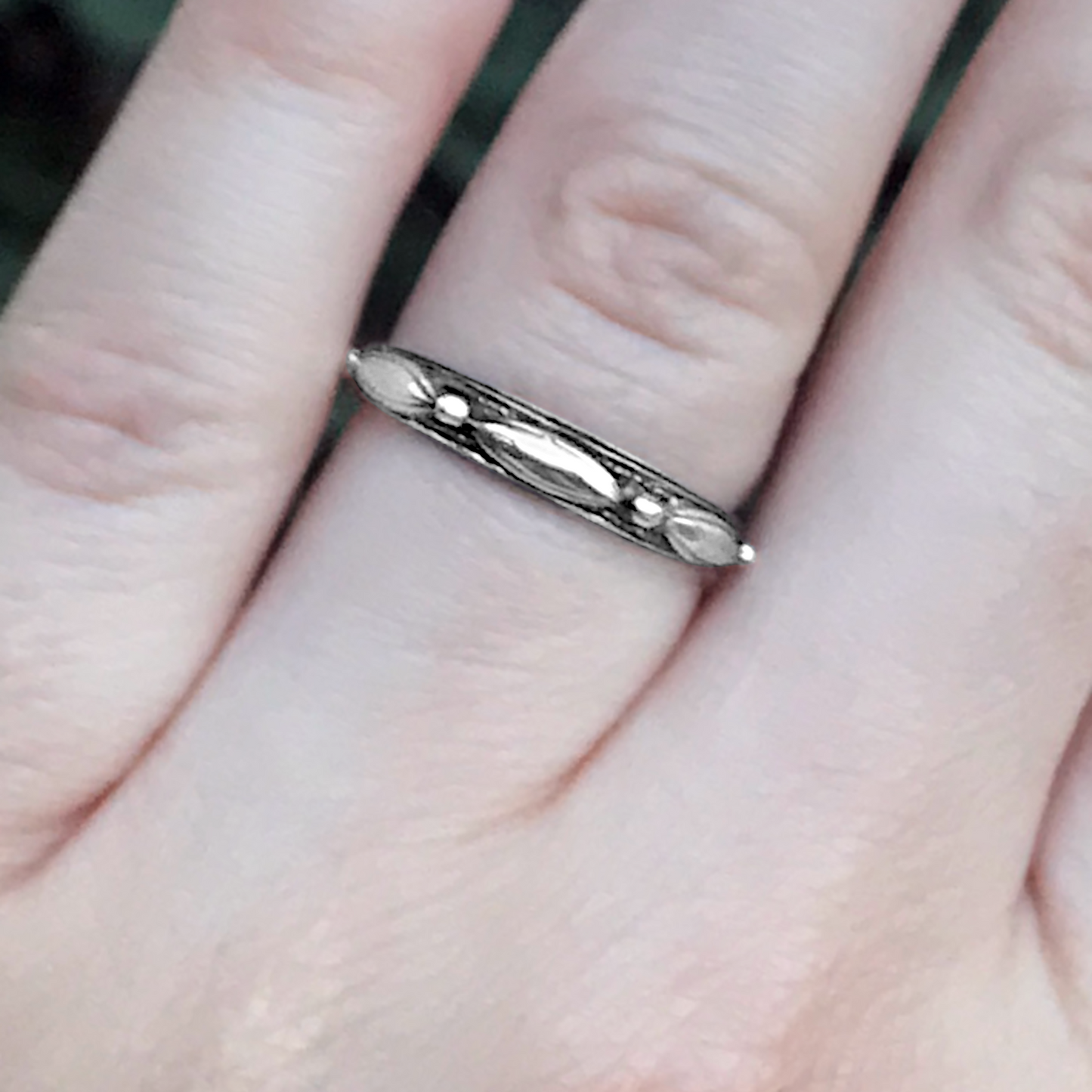 "Touch of Silver" Ring, in a close-up view on a finger, clearly showing the repeating oval and dot pattern on the band.