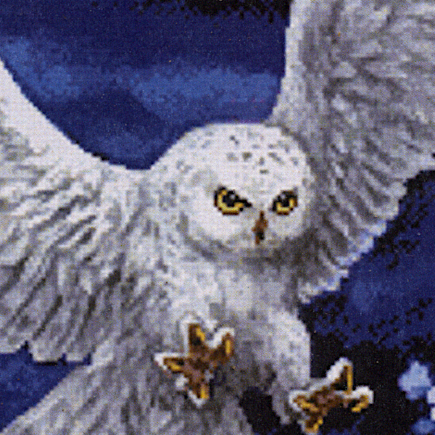 Close-up of the White Owl Cross Stitch Pattern featuring the owl’s piercing yellow eyes and outstretched talons as it hunts.