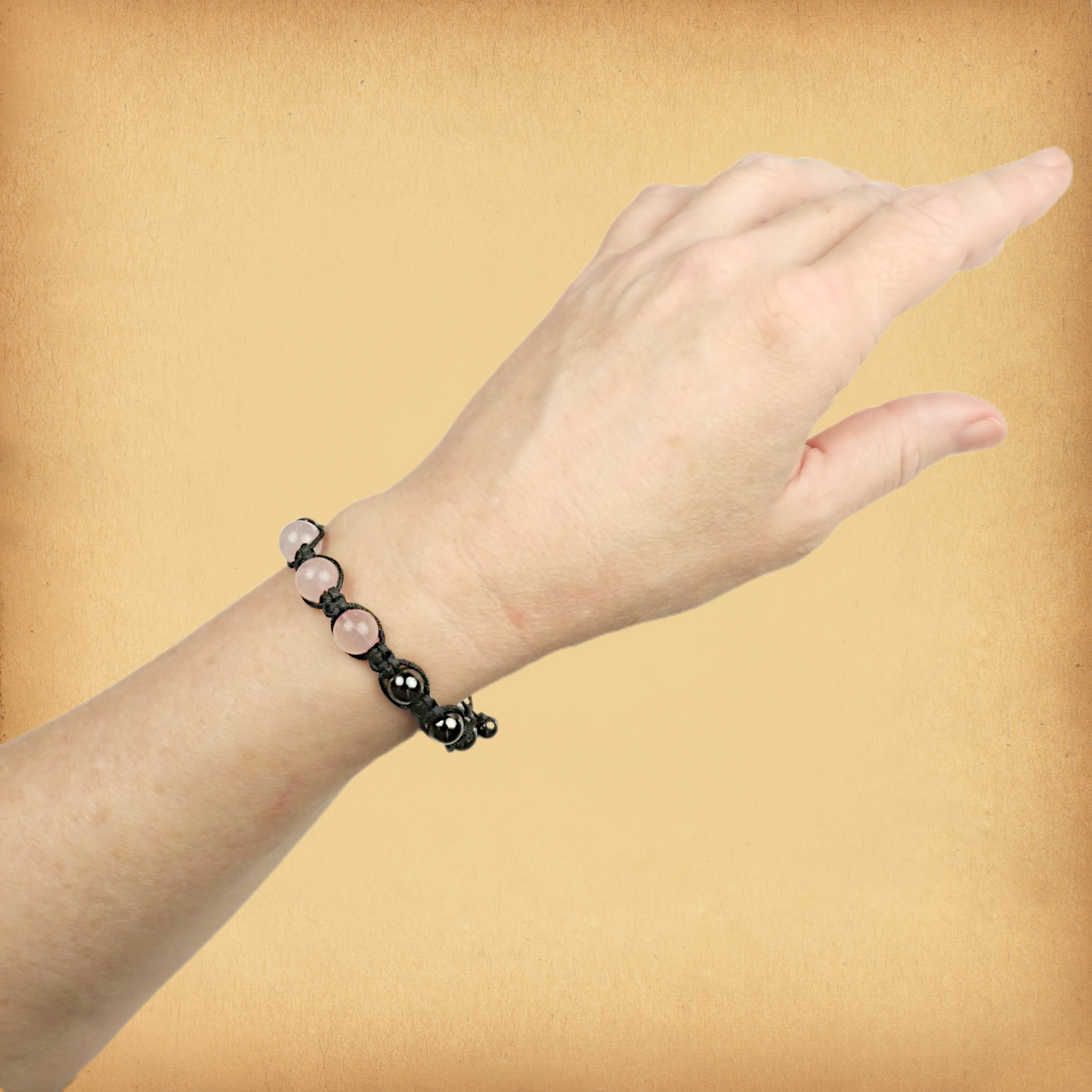 Rose Quartz Shamballa Bracelet being worn on a female wrist, showing the three larger rosy pink accent beads.