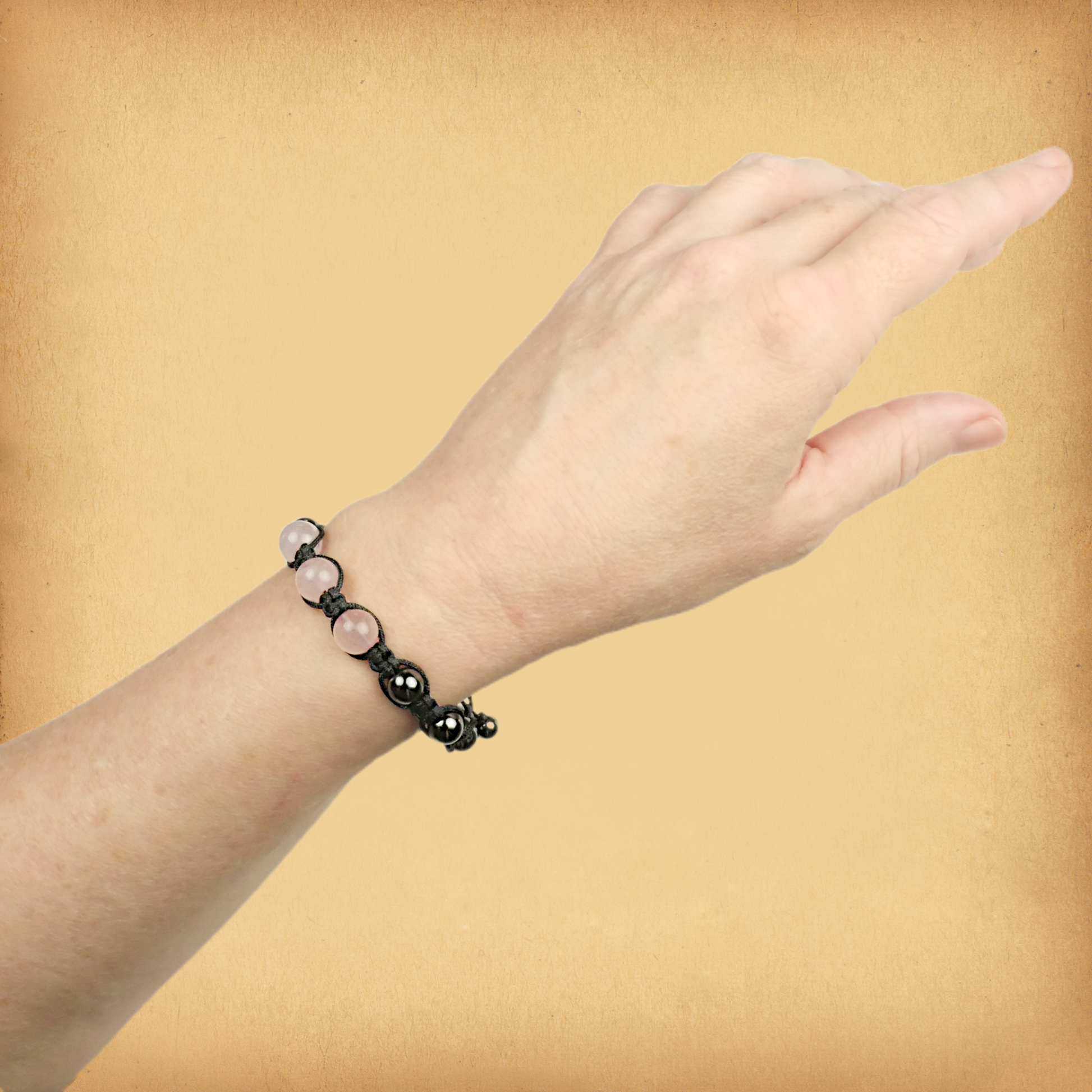 Rose Quartz Shamballa Bracelet being worn on a female wrist, showing the three larger rosy pink accent beads.