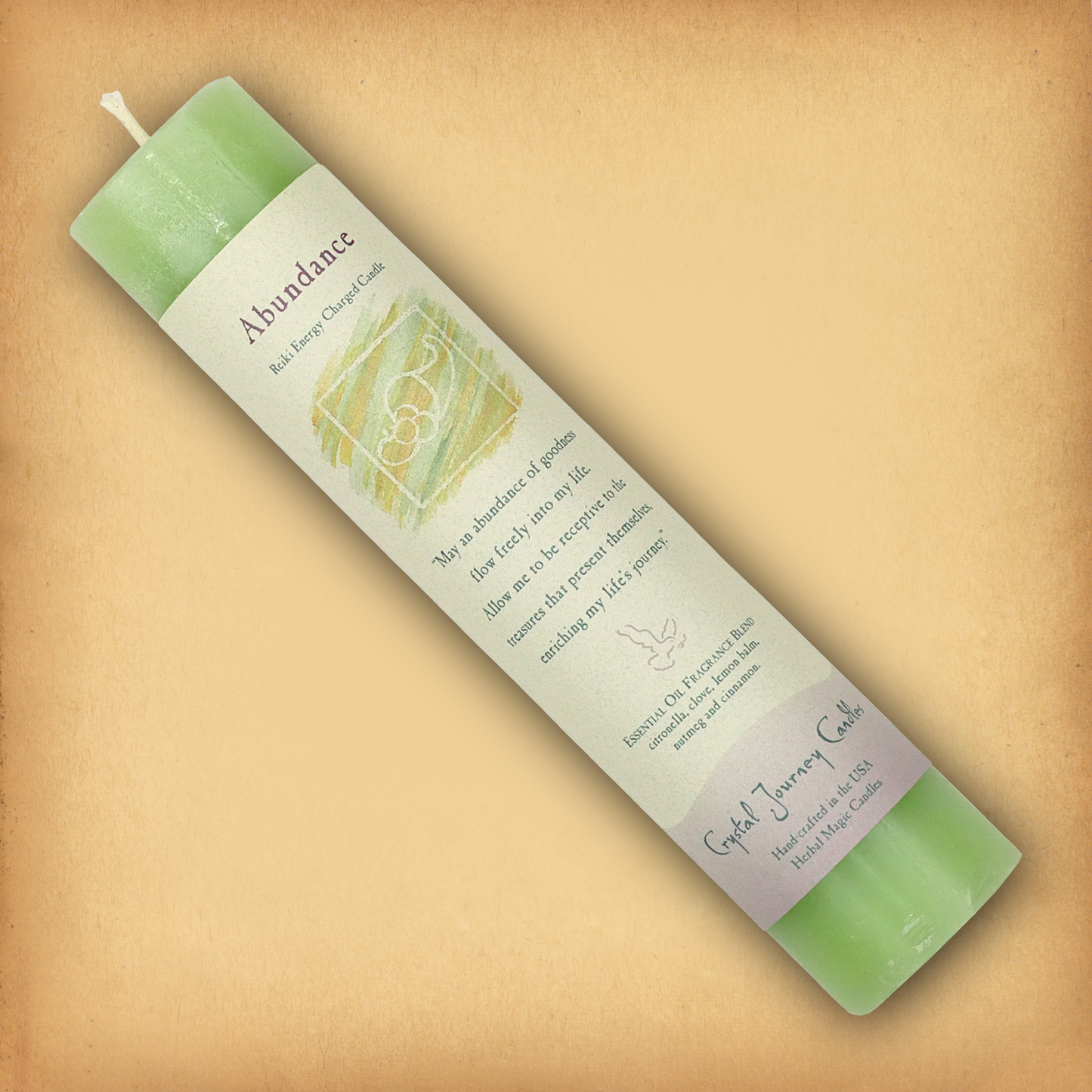 Green Reiki-charged Abundance Pillar Candle, displayed diagonally to show its label with affirmation and essential oil blend.