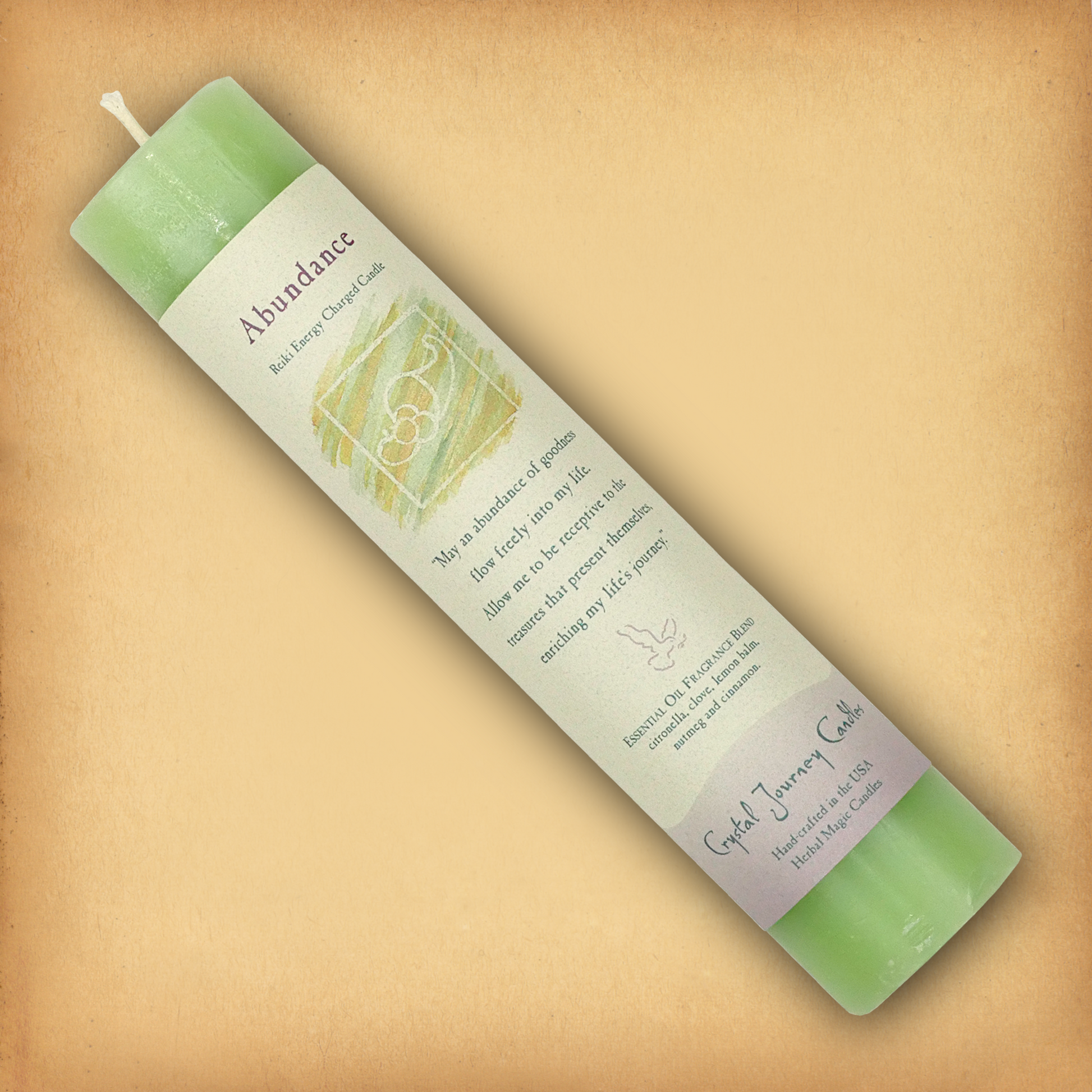 Green Reiki-charged Abundance Pillar Candle, displayed diagonally to show its label with affirmation and essential oil blend.