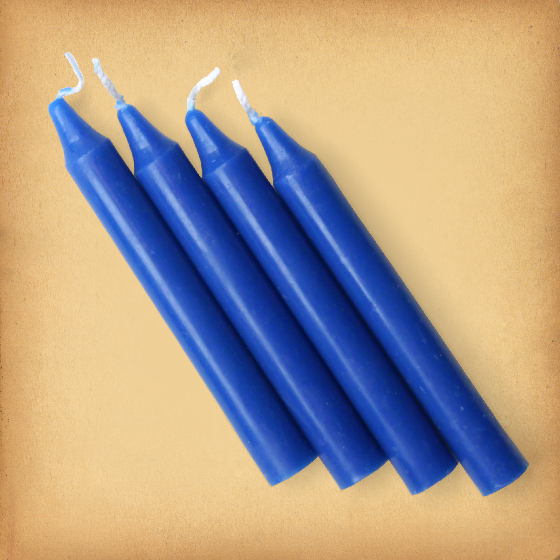 An overhead view of four royal Blue Chime Candles, diagonally placed on a plain surface, showing the candles' proportions.