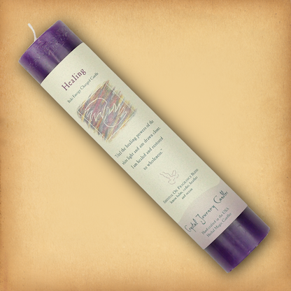 Purple Reiki-charged Healing Pillar Candle, displayed diagonally to show its label with affirmation and essential oil blend.