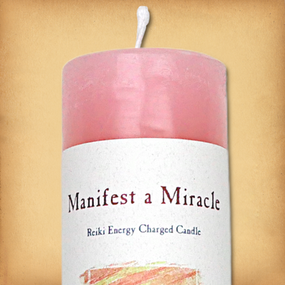 Pink pillar candle labeled “Manifest a Miracle” with “Reiki Energy Charged Candle” beneath. Slim pillar candle, single wick.
