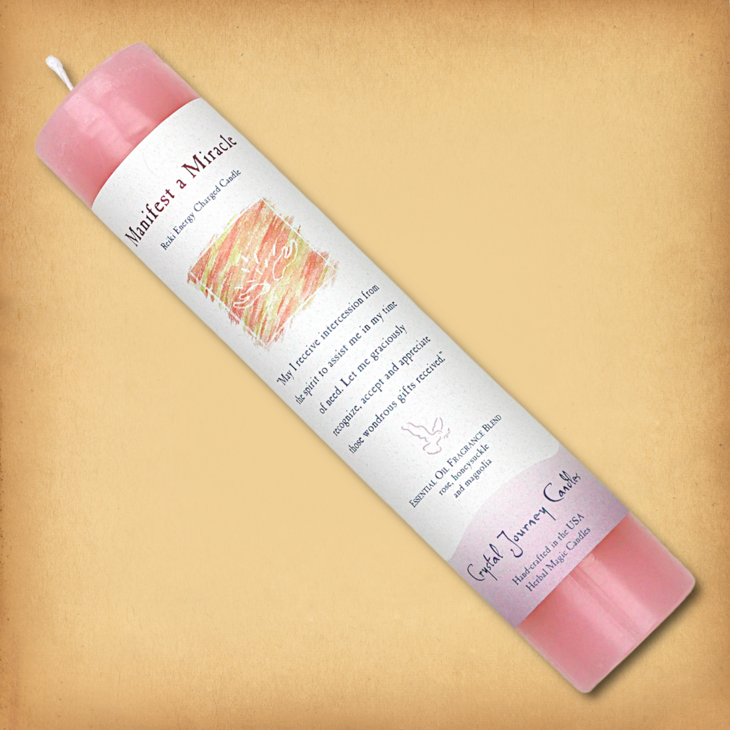 Pink Reiki-charged Manifest a Miracle Pillar Candle, laid diagonally to show label with affirmation and essential oil blend.