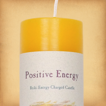 Yellow pillar candle labeled “Positive Energy” with “Reiki Energy Charged Candle” beneath. Slim pillar candle w/ single wick.