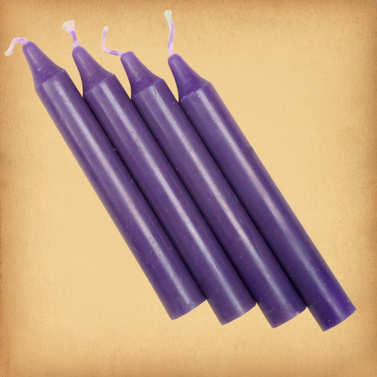 An overhead view of four Purple Chime Candles, diagonally placed on a plain surface, showing the candles' proportions.