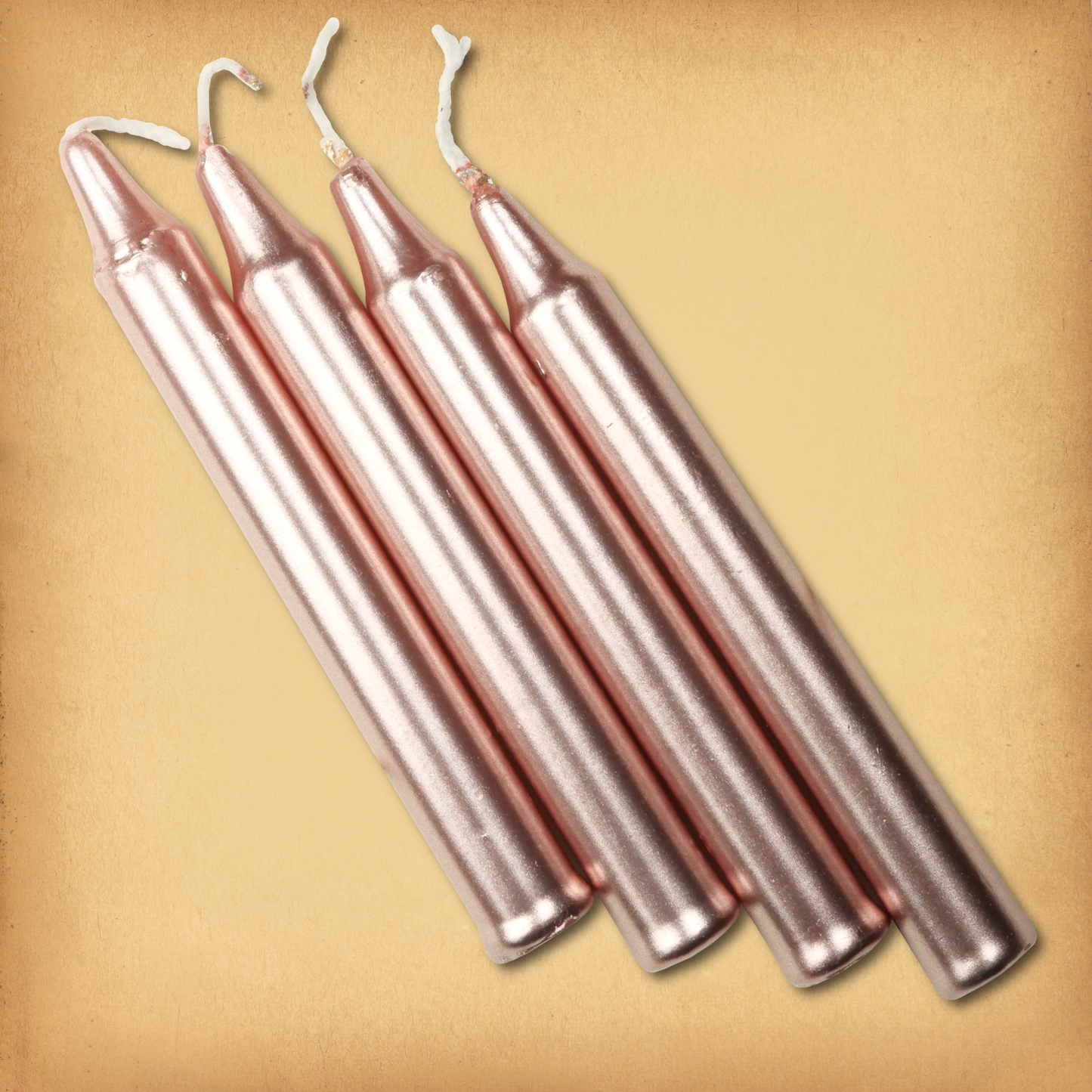 An overhead view of four Rose Gold Chime Candles, diagonally placed on a plain surface, showing the candles' proportions.