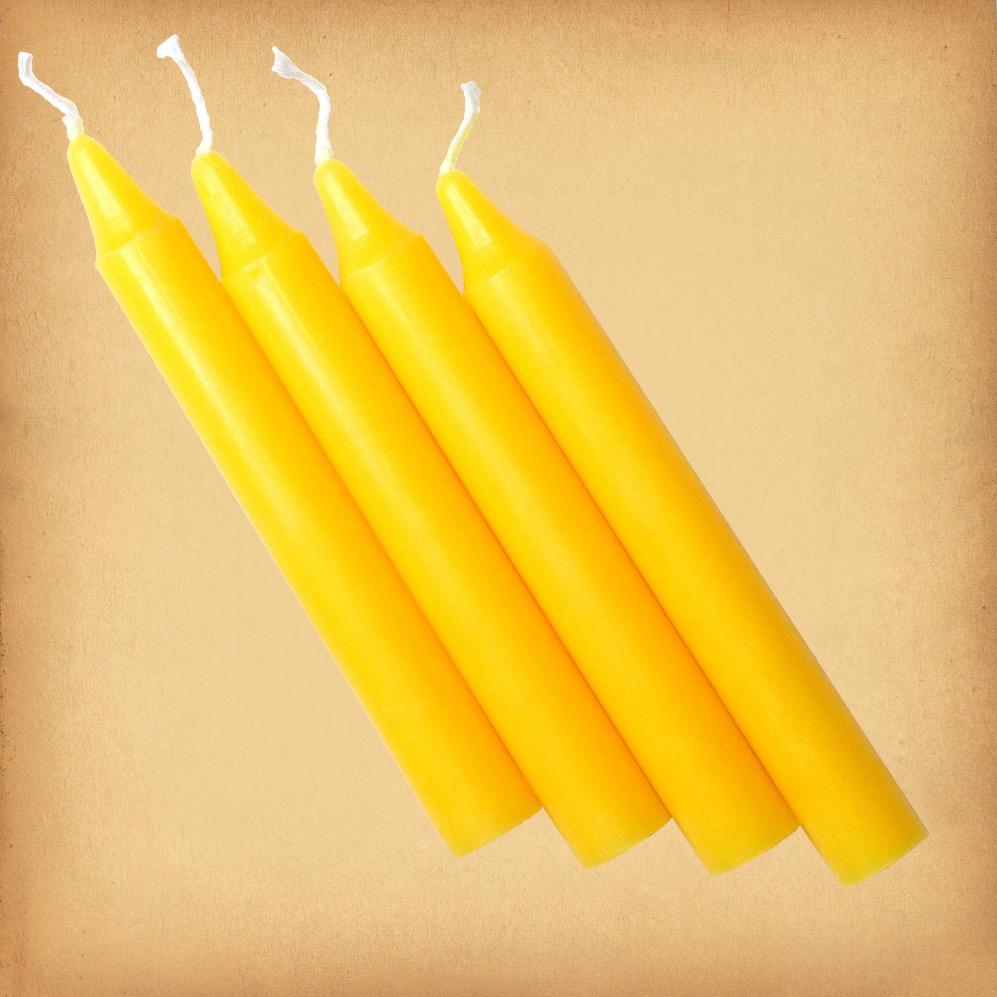 An overhead view of four Yellow Chime Candles, diagonally placed on a plain surface, showing the candles' proportions.