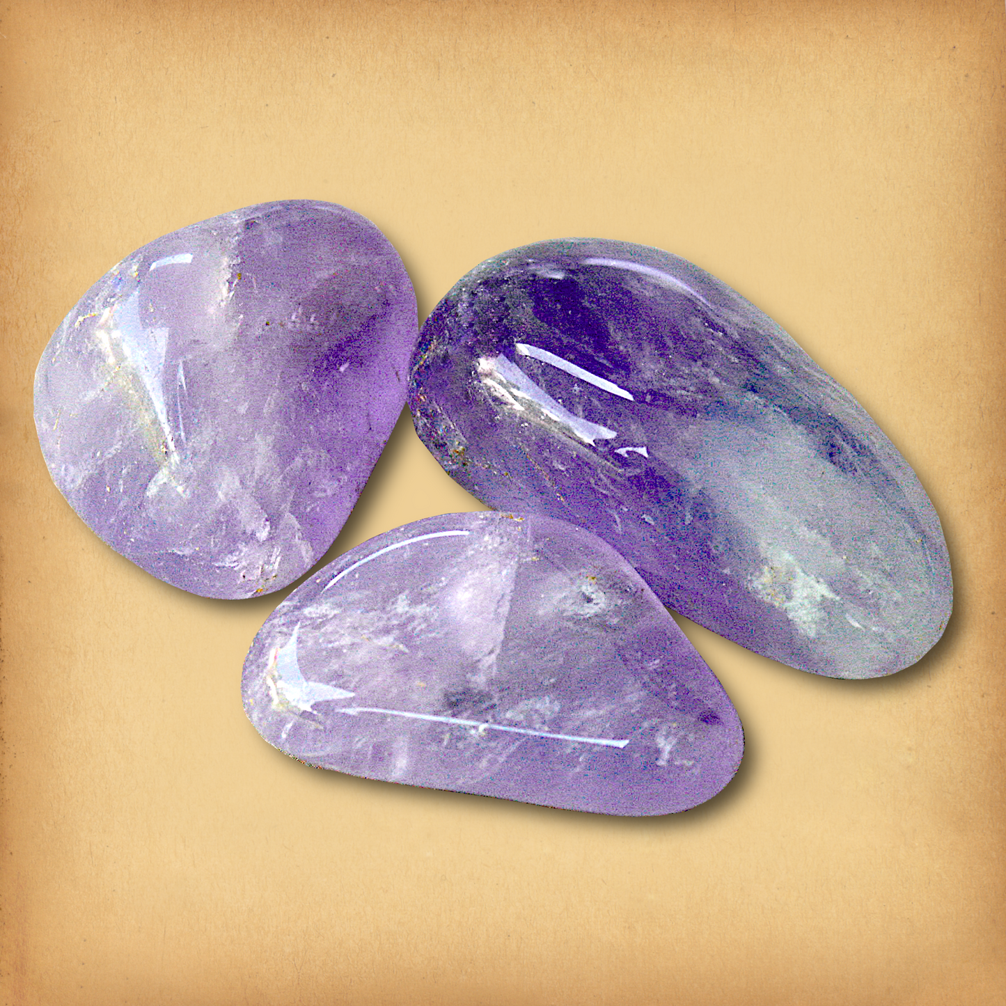 Three tumbled Amethyst stones, in soft lavender to deep purple hues, demonstrating the typical variety in a set.