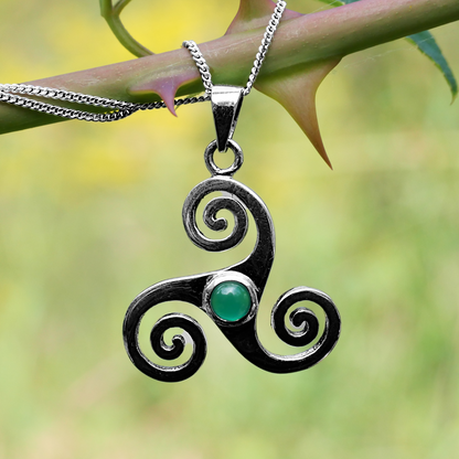 Sterling Silver Triskele Pendant with green agate, draped over a rose stem with thorns, highlighting its dramatic silhouette.