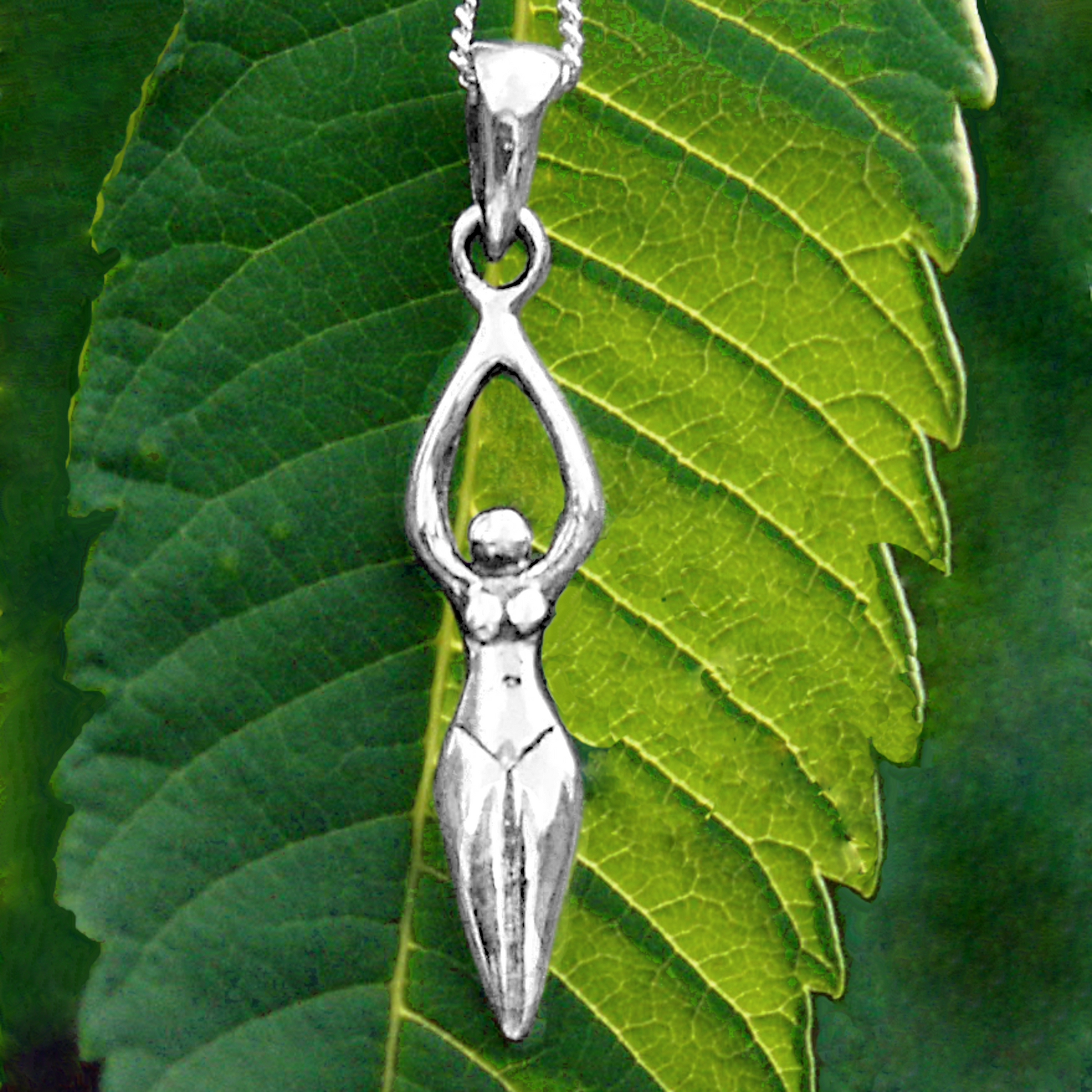 Sterling Silver Goddess Pendant with a stylized female form, displayed on a vibrant green leaf, symbolizing sacred energy.