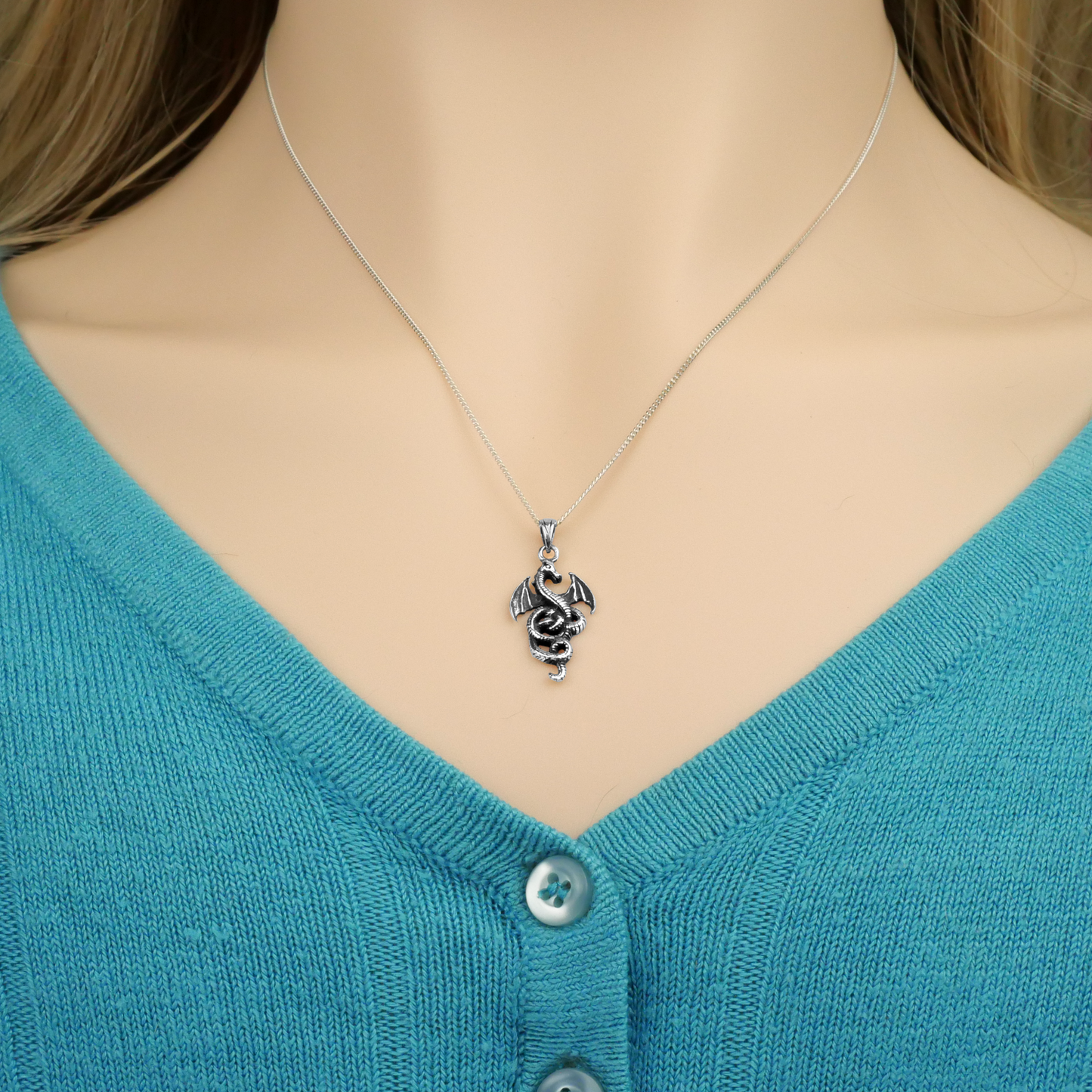 Sterling Silver Coiled Dragon Pendant worn by a model, showing the pendant hanging just above the V-neck of her sweater.