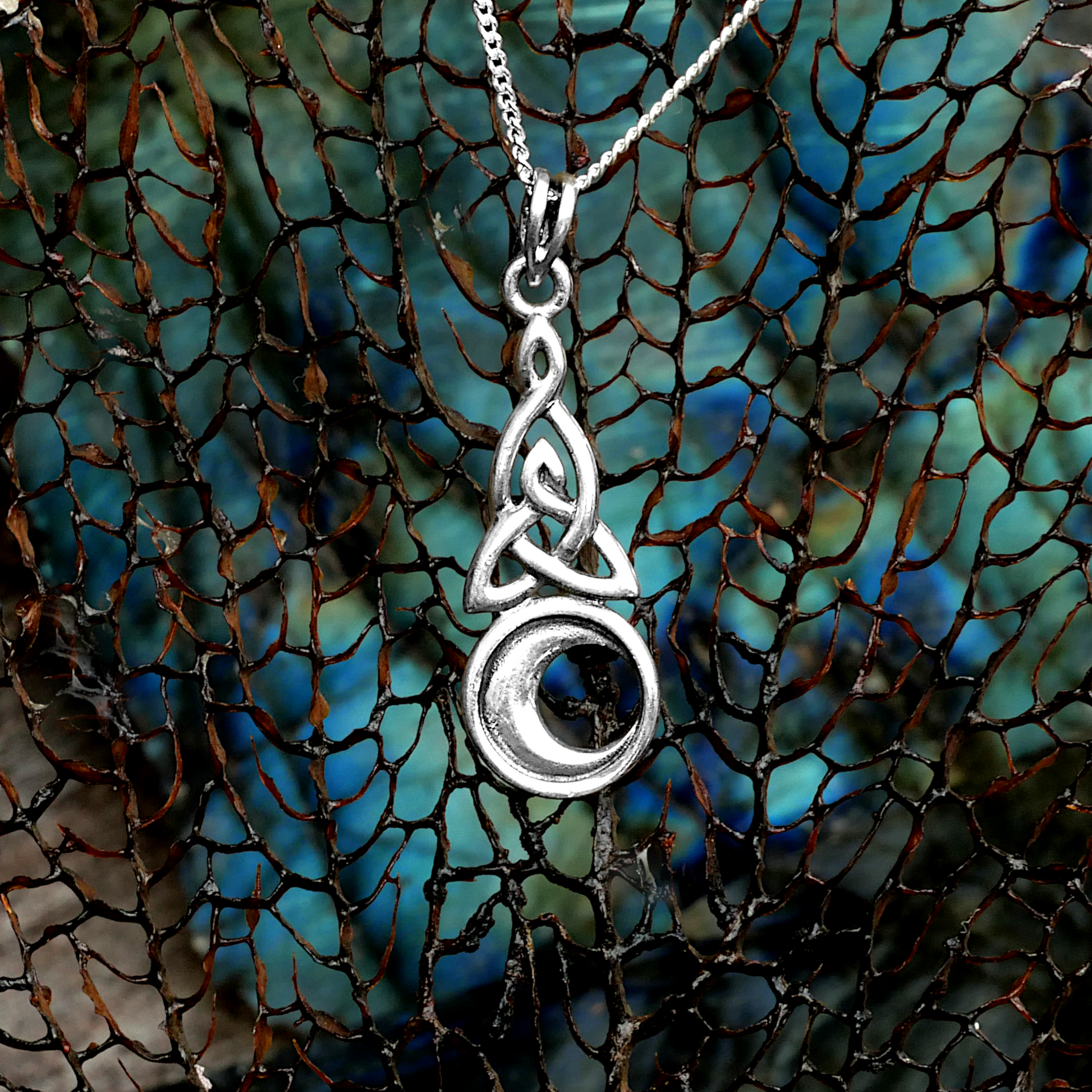 Sterling Silver Celtic Moon Pendant displayed on blue-green labradorite, blending Celtic knotwork with lunar symbolism