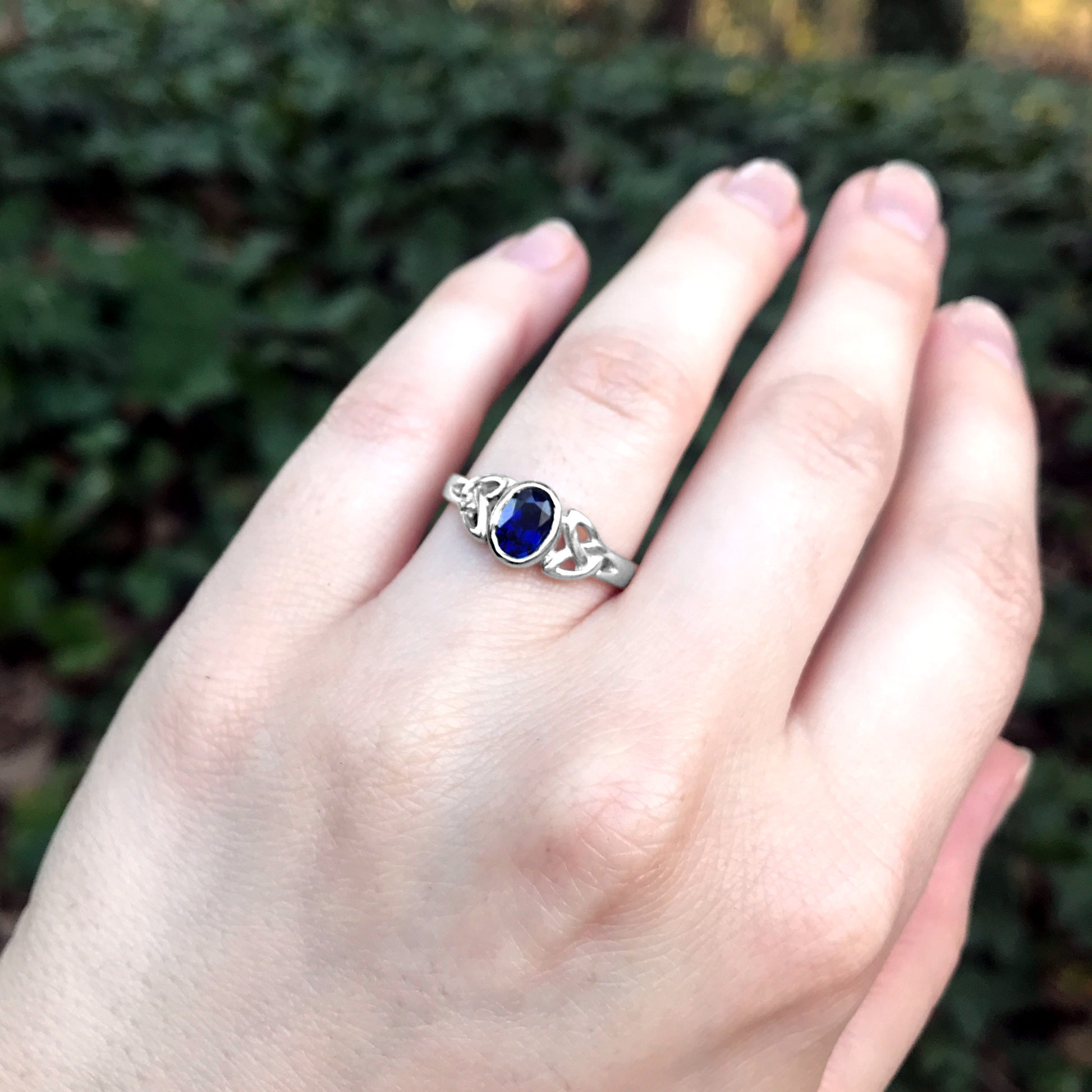 Sterling Silver Sapphire Celtic Ring, worn on a hand, showcasing its Celtic-insired design and faceted sapphire centerpiece.