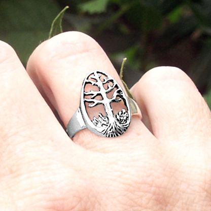 Close-up of a Sterling Silver Tree of Life Ring worn on a hand, showcasing its openwork design with branches and roots.