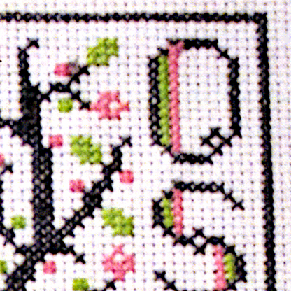 Close-up of a stitched section of the Blessed Ostara cross stitch design showing lettering, floral details, and simple border