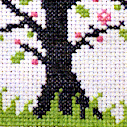 Close-up of a stitched section of the Blessed Ostara cross stitch design, highlighting the vivid pink and spring green colors